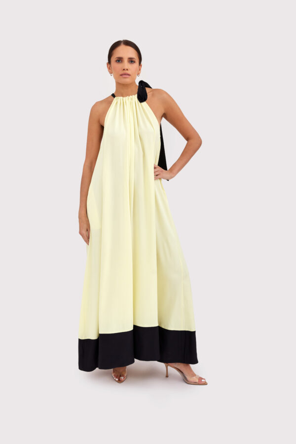 Modelka w letniej sukience maxi w kolorze maślanym, z czarnym wiązaniem na szyi – stylizacja Yellow Mood na lato