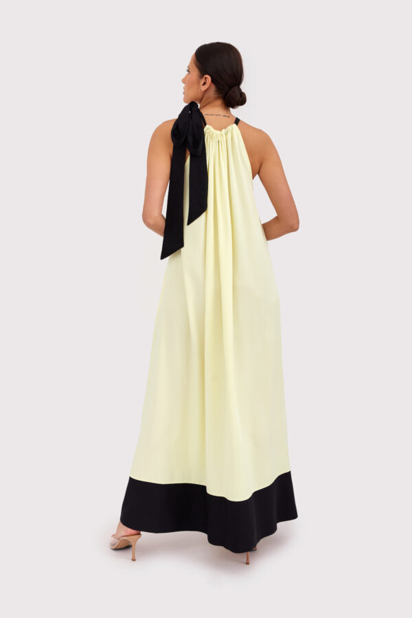 Modelka w letniej sukience maxi w kolorze maślanym, z czarnym wiązaniem na szyi – stylizacja Yellow Mood na lato